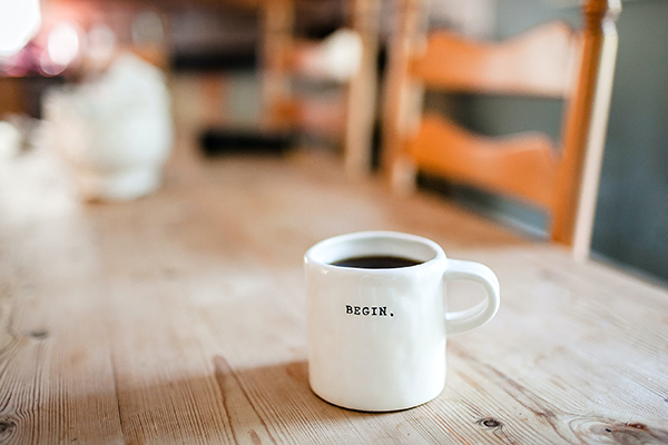 Coffee cup on a table has 'begin' written on it.