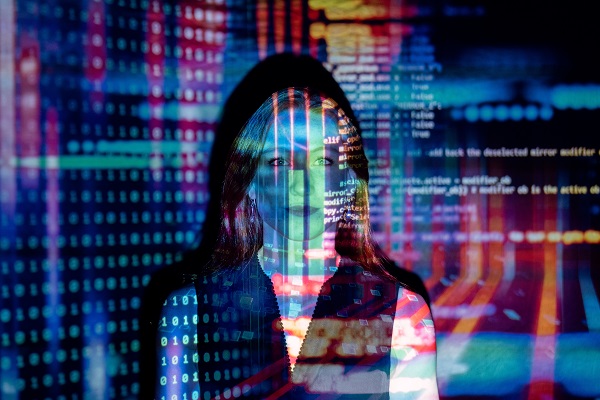 A woman stands against a wall, coloured coding projected across her.