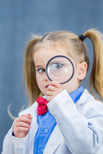 Girl holding magnifying glass to her eye